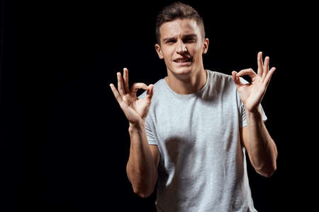 handsome man in white t-shirt on black background inflated arm muscles sport model cropped view Copy...