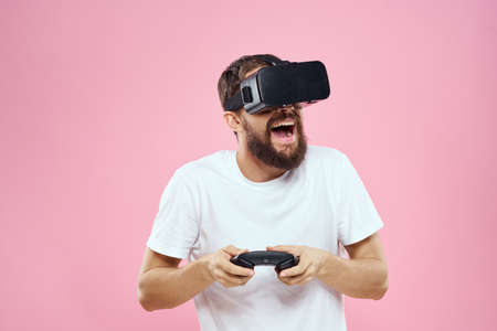 Man in virtual reality glasses joystick playing video lifestyle white t-shirt pink background