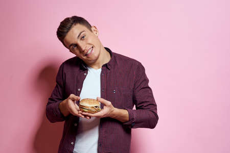 hungry man with hamburgers in hands fast food diet food emotions pink background
