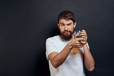 Man with a mug of beer in his hands emotions fun lifestyle white t-shirt dark isolated background
