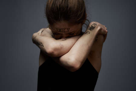 woman with offensive inscriptions on her body touching herself with hands stress frustration hateの写真素材