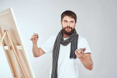 A man artist draws on an easel a scarf white t-shirt art hobby creativityの写真素材