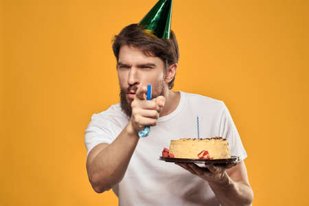 A bearded man with a cake and in a cap celebrating his birthdayの写真素材