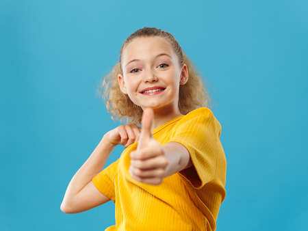 teenager girl in yellow t-shirt showing thumb on isolated backgroundの写真素材
