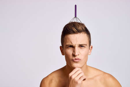 man with iron head massager on a light background naked torso model beautiful face