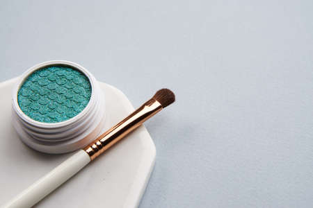 Green eyeshadow and makeup brush on white stand isolated backgroundの写真素材