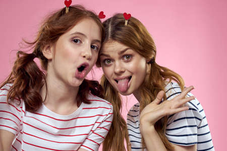 Cheerful mom and daughter lifestyle joy striped shirts family pink background