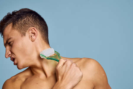 naked man with a massage instrument in his hand on a blue background emotions open mouth modelの写真素材