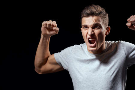handsome man in white t-shirt on black background inflated arm muscles sport modelの写真素材