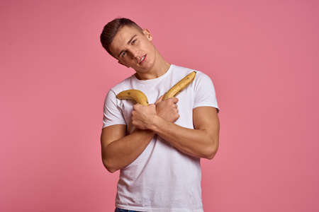 Man with fruits in hands on a pink background healthy food vitamins pink background white t-shirt modelの写真素材