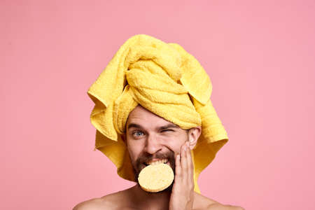 man with yellow towel on his head sponge clean skin care pink backgroundの写真素材