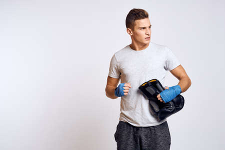 Strong man with boxing gloves and in a white t-shirt on an isolated background cropped view of the...