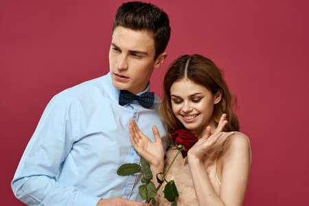 portrait of romantic couple in love with red rose on isolated background and classic suit evening...