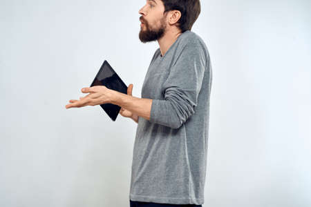 A man with a tablet in his hand internet technology communication gray jacket light background