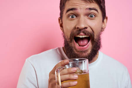Bearded man with a mug of beer On a pink background fun emotions cropped view of a white T-shirt drunkの写真素材