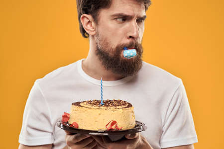 A bearded man with a cake and in a cap celebrating his birthdayの写真素材