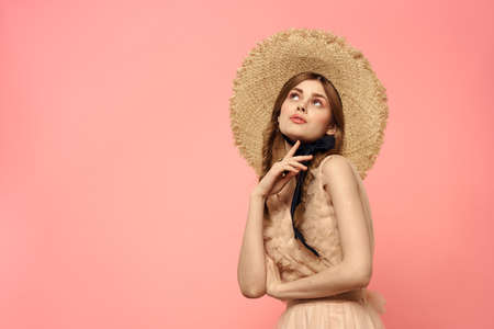 Fashionable woman in dress and hat with black ribbon on pink background cropped view of model...
