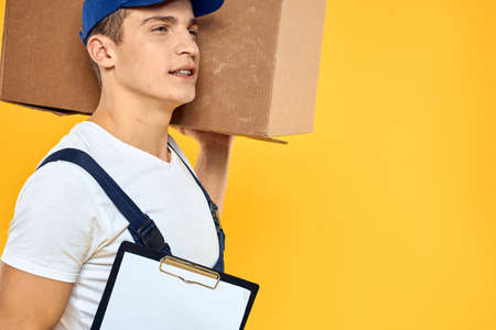 Working man in uniform with box hand delivery loading service yellow background