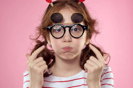 Cheerful girl with pigtails sunglasses striped t-shirt lifestyle pink background