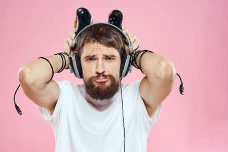 Man in headphones with joysticks in hands playing games lifestyle fun entertainment pink backgroundの写真素材