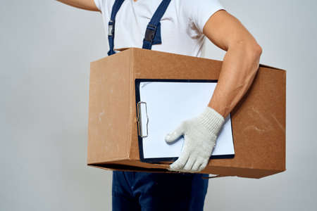 Man worker with box in hands delivery loading service work light backgroundの写真素材
