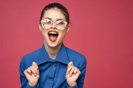 Portrait of a woman in glasses and in a blue shirt red lips pink background model