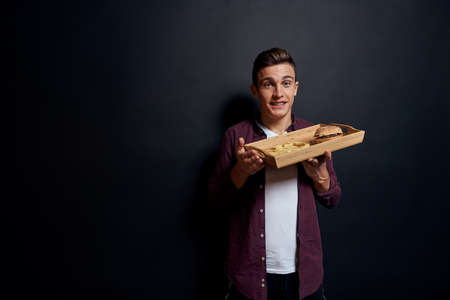 man holding wooden pallet with fast food in his hands diet food hunger lifestyle dark background