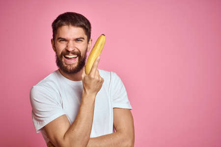 bearded man with banana in hand on pink background fun emotions modelの写真素材