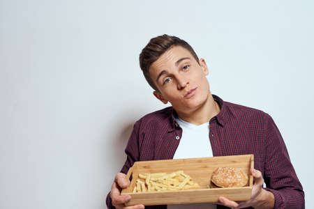 Man eating wooden pallet fast food french fries hamburger diet food restaurant light backgroundの写真素材