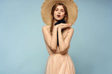 Girl in a pink dress on a blue background gestures with her hands romance model fun emotions cropped...