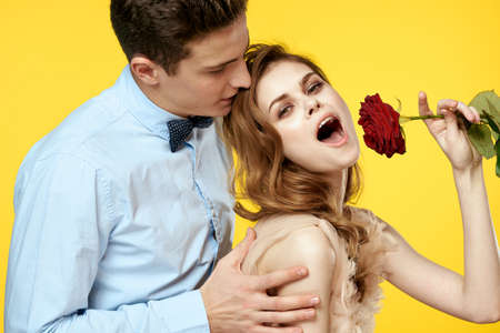 Enamored man and woman with red rose on yellow background cropped view close-up romance