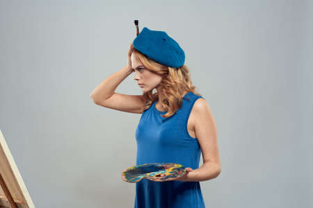 woman artist blue beret palette drawing on easel art creativity light backgroundの写真素材