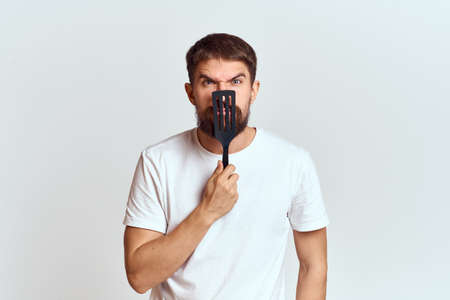 man with cooking shovel and white t-shirt close-up cropped view emotion gesturing with hand