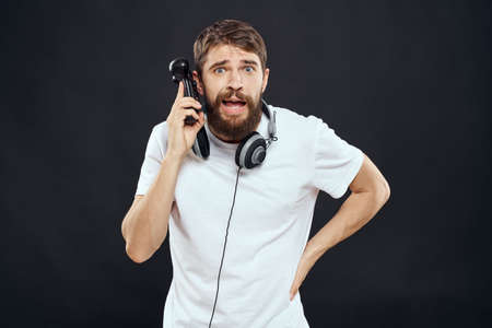 Man with joystick in hands headphones technology leisure game lifestyle dark isolated backgroundの写真素材