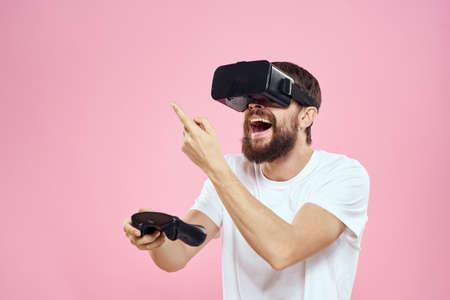 Man in virtual reality glasses joystick playing video lifestyle white t-shirt pink background