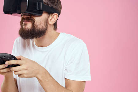 Man in virtual reality glasses joystick playing video lifestyle white t-shirt pink backgroundの写真素材