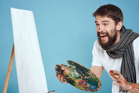 Male artist palette brush easel art hobby blue backgroundの写真素材