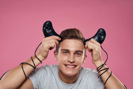 A man holds over his head joysticks wires on his hands entertainment leisure lifestyle games pink...