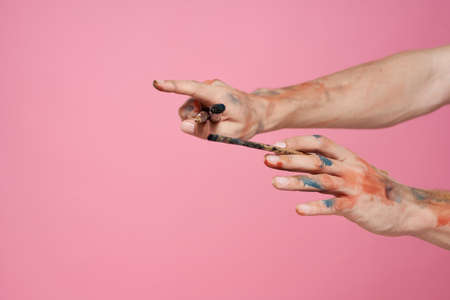 Man with brushes in hands paint on pink backgroundの写真素材