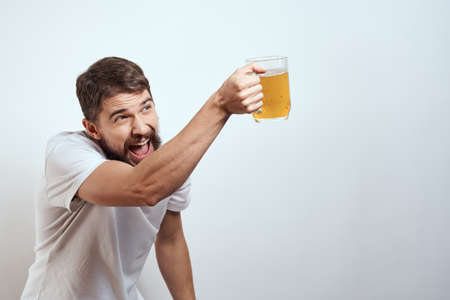 man with a mug of beer in his hands and a white t-shirt light background mustache beard emotions...