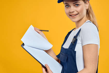 woman in work uniform documents courier service yellow backgroundの写真素材