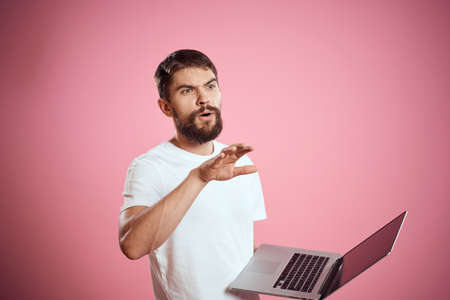 A man with an open laptop white t-shirt gestures with his hands cropped view new technology keyboard...