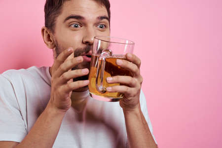 Bearded man with a mug of beer On a pink background fun emotions cropped view of a white T-shirt drunkの写真素材