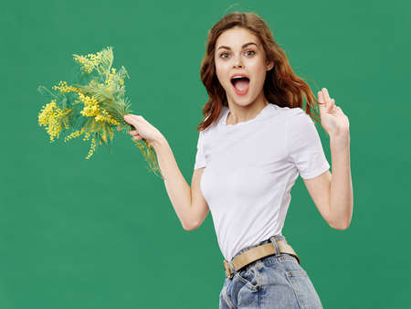 Delighted woman with a bouquet of flowers gestures with her handsの写真素材