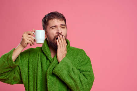 Man with a cup of tea on a pink background cropped view of emotion model green robeの写真素材
