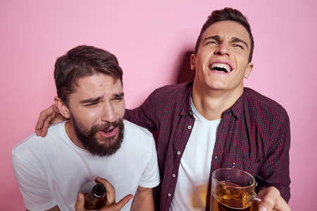 Two men drink beer friendship drunk alcohol lifestyle pink backgroundの写真素材