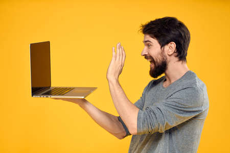 man with laptop wireless technology internet lifestyle work yellow isolated backgroundの写真素材