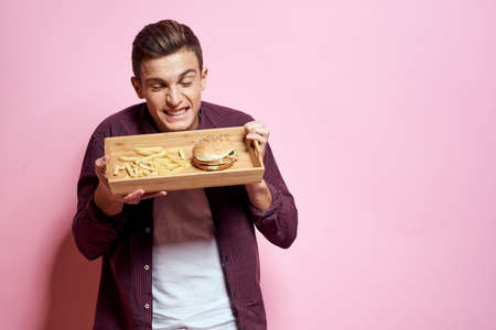 Man with wooden pallet fast food diet food lifestyle pink backgroundの写真素材