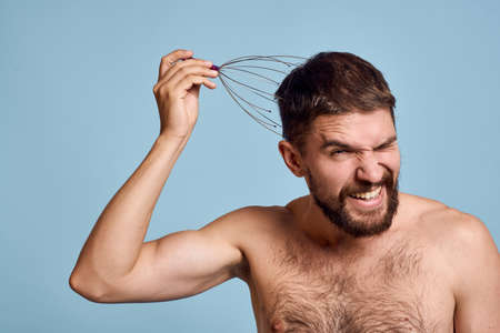 Man with naked shoulders head massager healthy lifestyle blue backgroundの写真素材