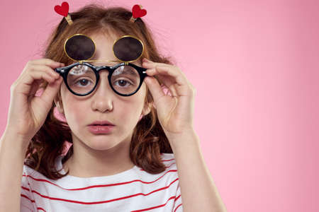 Cheerful girl with pigtails sunglasses striped t-shirt lifestyle pink backgroundの写真素材
